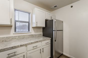 A kitchen with a black refrigerator and white cabinets.